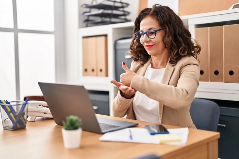 Profissional sinalizando em Libras para a câmera do notebook no escritório